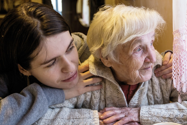 A senior being hugged by a young adult