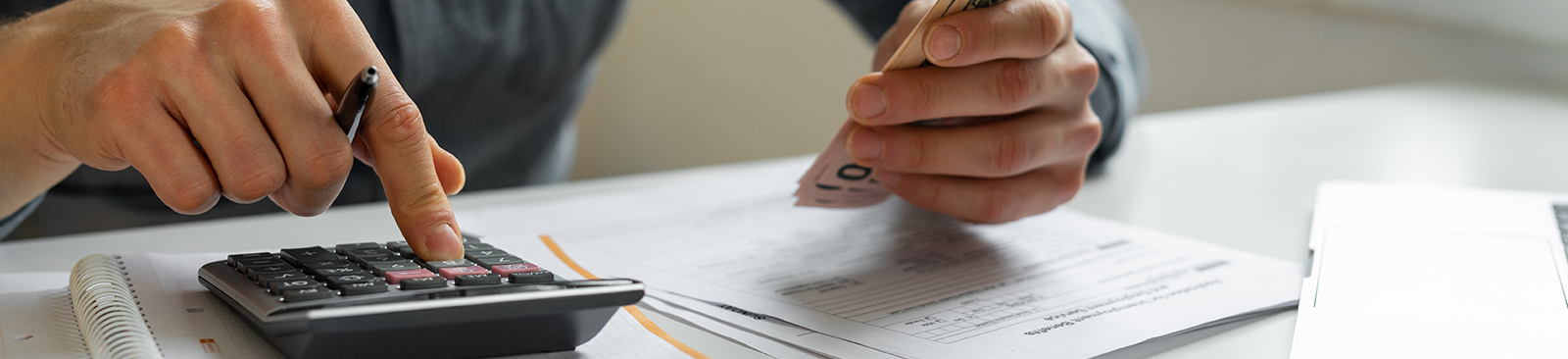 Close up of a person's hands using a calculator to count money and pay expenses