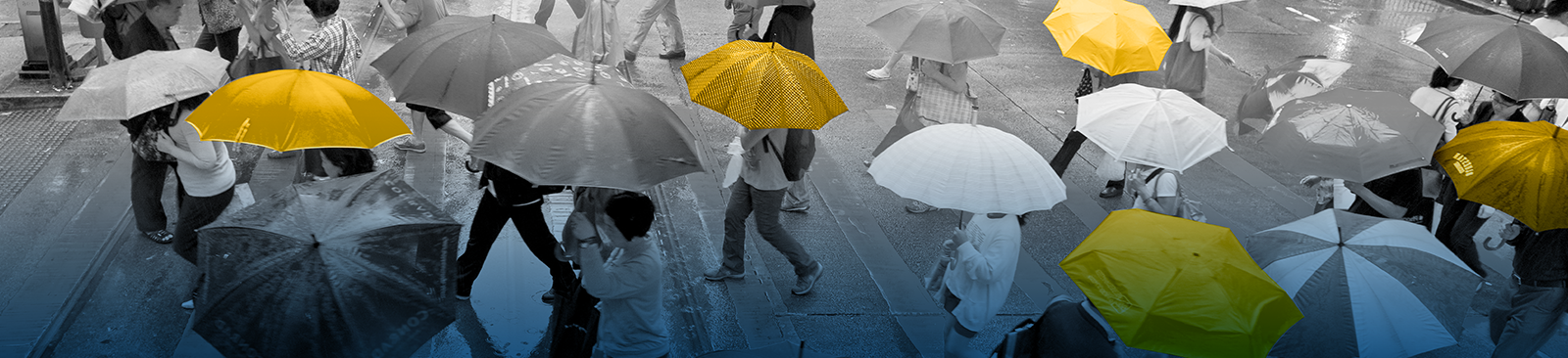 A person stands with their back to the camera, carrying a bright yellow umbrella in the middle of a storm. They stand on a pier, looking out at the stormy sky, which simultaneously looks threatening and hopeful as some of the clouds part to reveal a glimpse of sunshine.